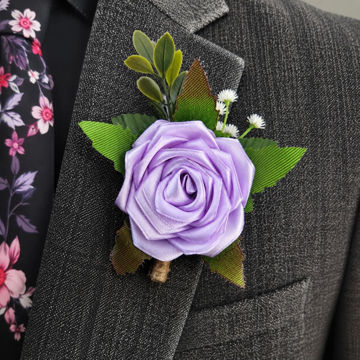 Light Orchid satin rose buttonhole attached to a formal grey suit jacket lapel