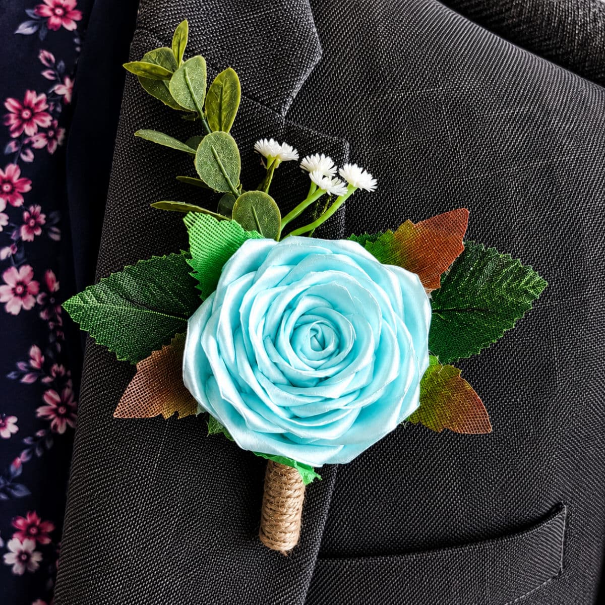 Aqua satin rose buttonhole attached to a formal grey suit jacket lapel