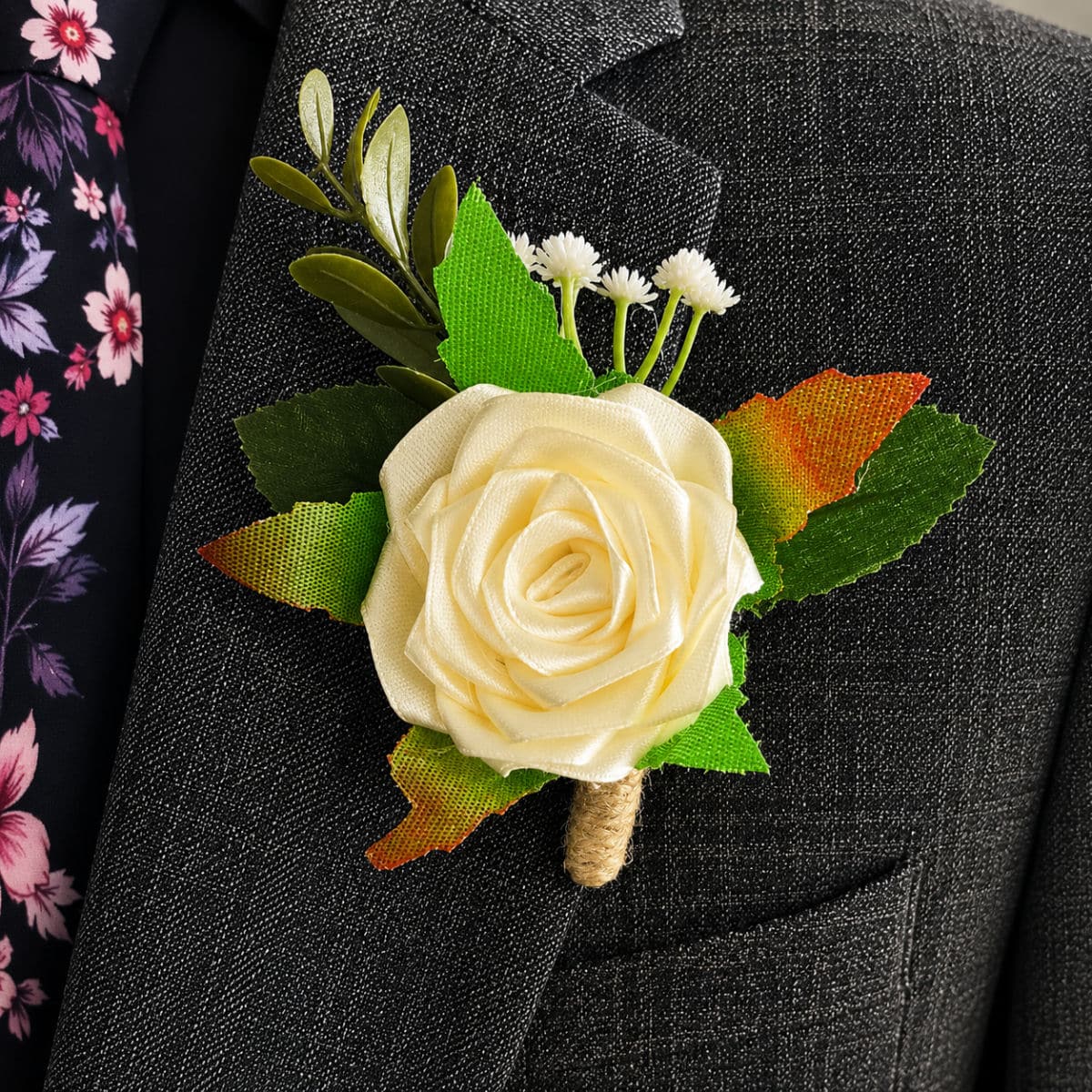 Cream satin rose buttonhole attached to a formal grey suit jacket lapel
