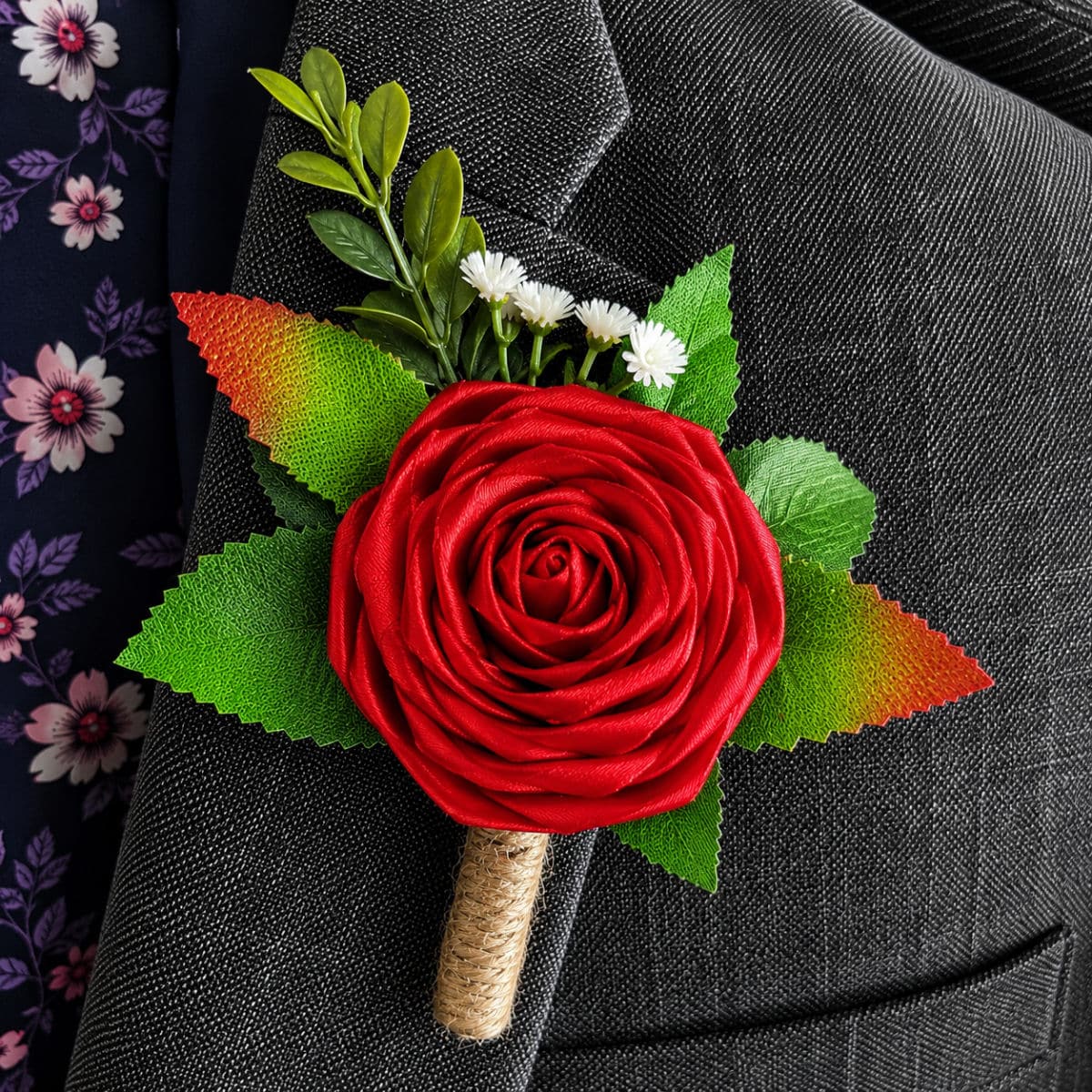 Red satin rose buttonhole attached to a formal grey suit jacket lapel